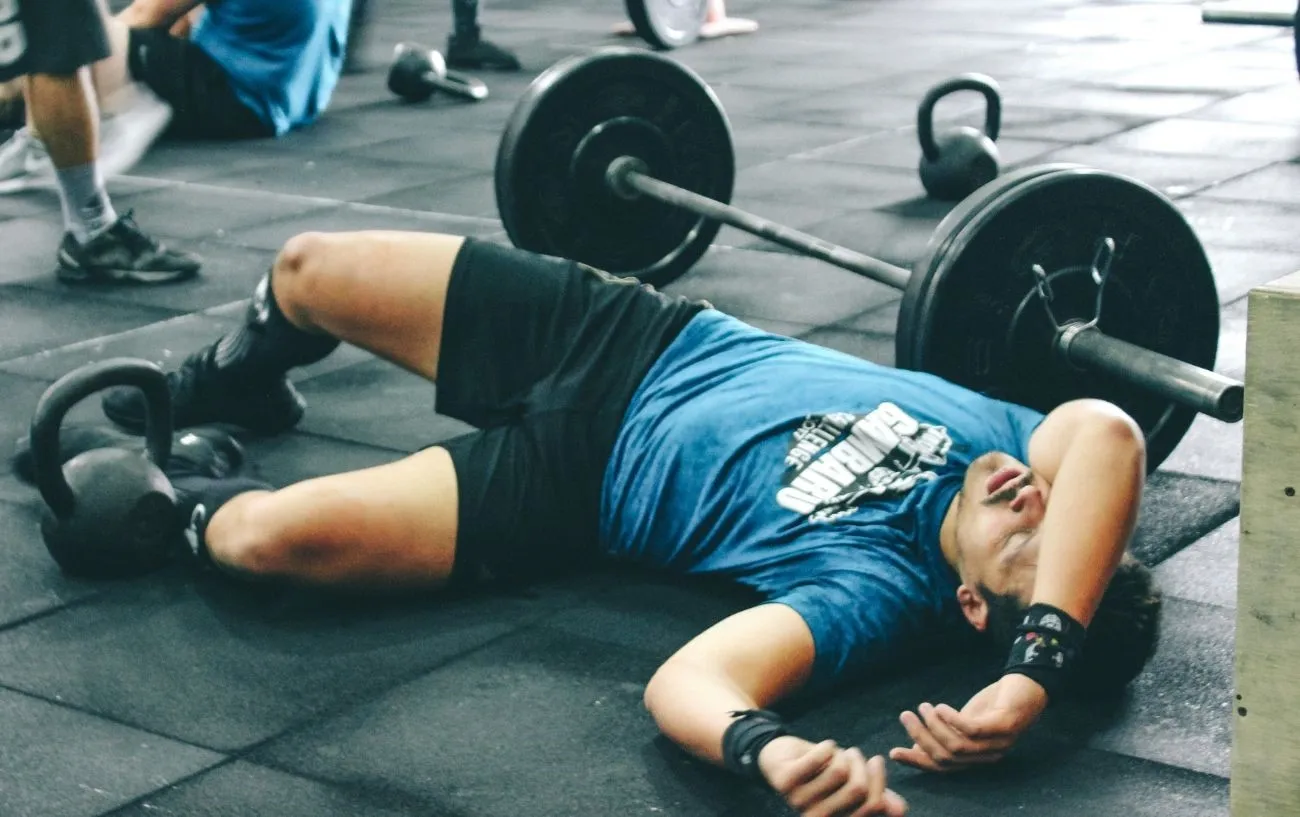 Атлет CrossFit лежит на земле, обессиленный.