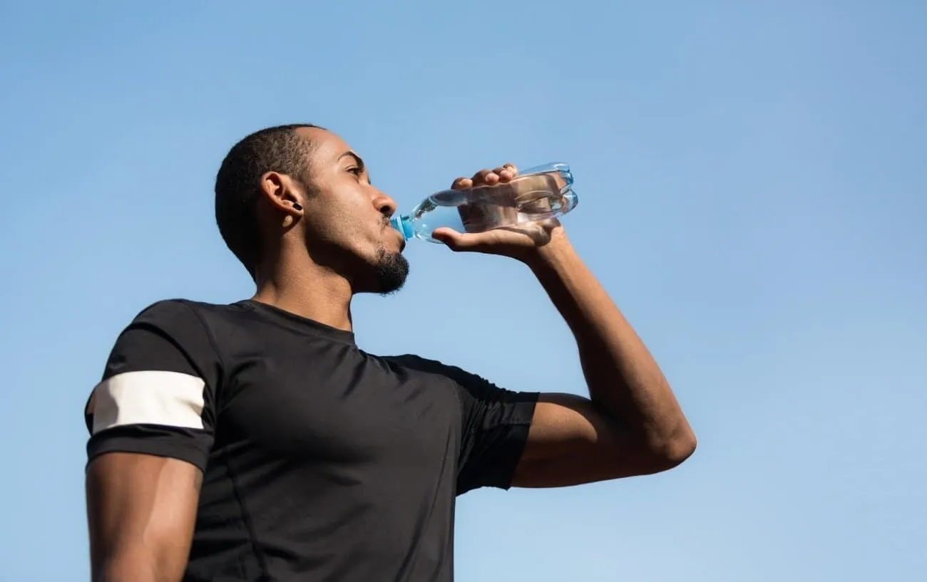 Мужчина пьет воду из бутылки. 