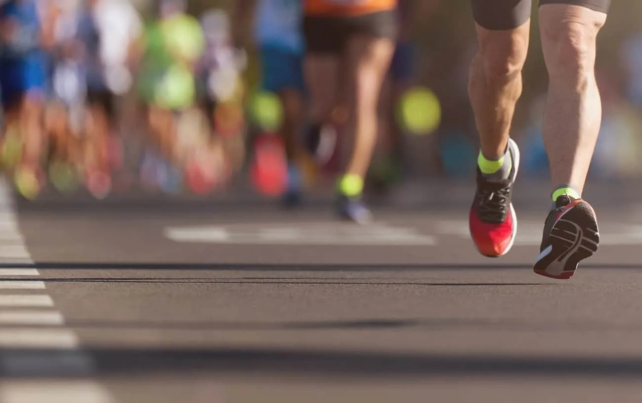 Размытая фотография людей's legs while they run a marathon.