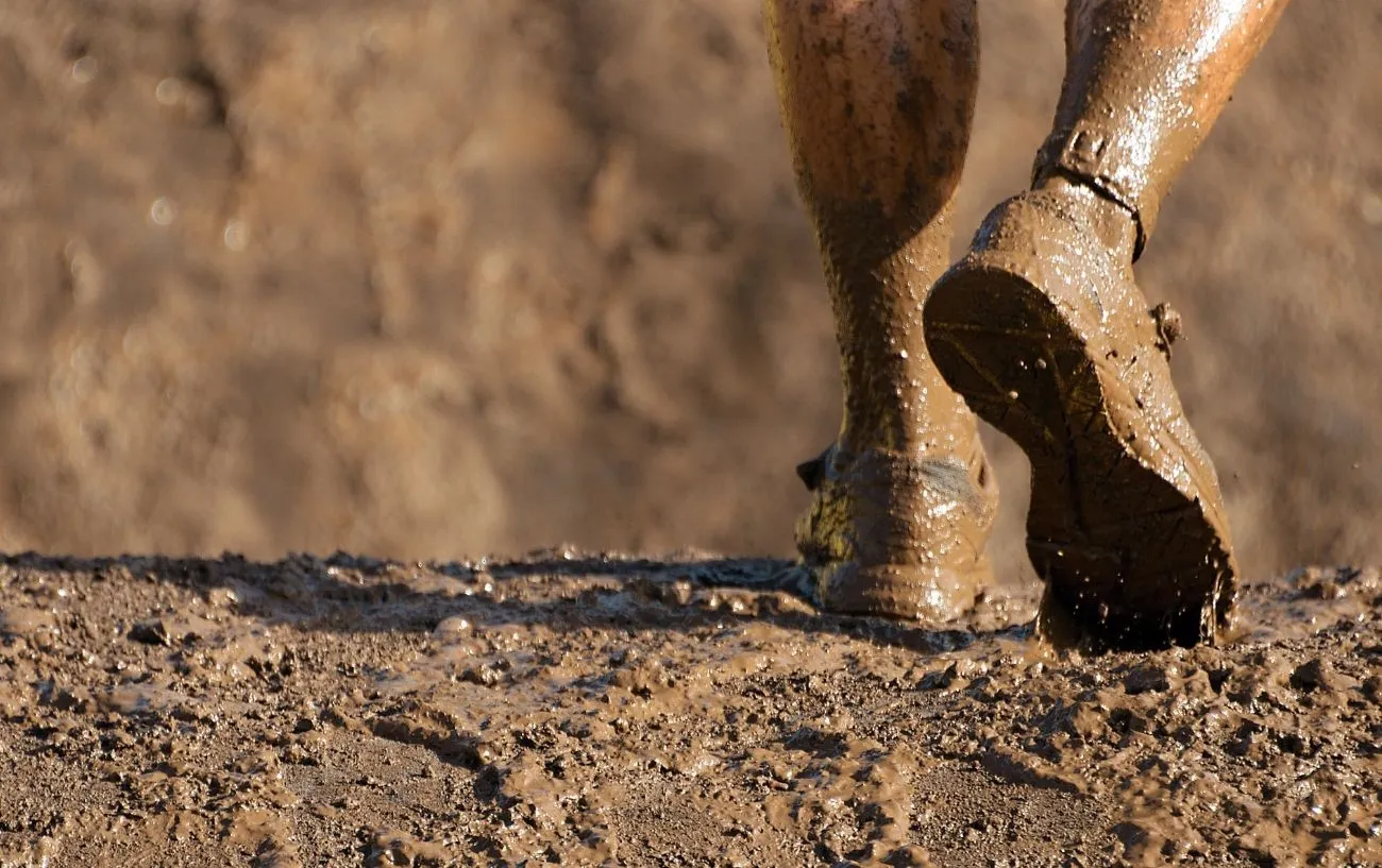 Бегун по тропе's shoes covered in mud.