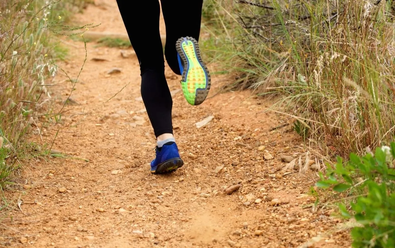 Крупный план бегуна's sneakers while running on a trail.