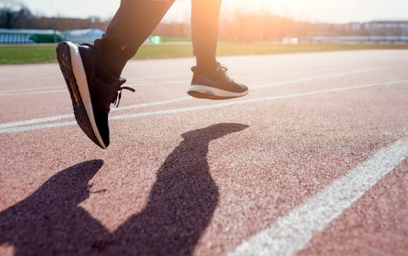 Крупный план бегуна's sneakers while running on a track.