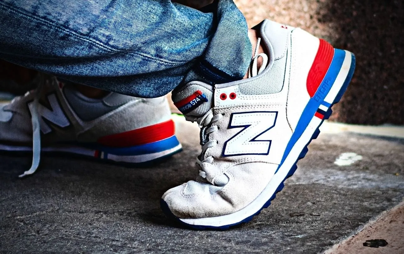 Человек наклоняется в кроссовках New Balance.