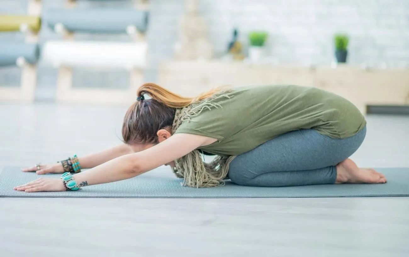 Человек, занимающийся ребенком's pose on a yoga mat.