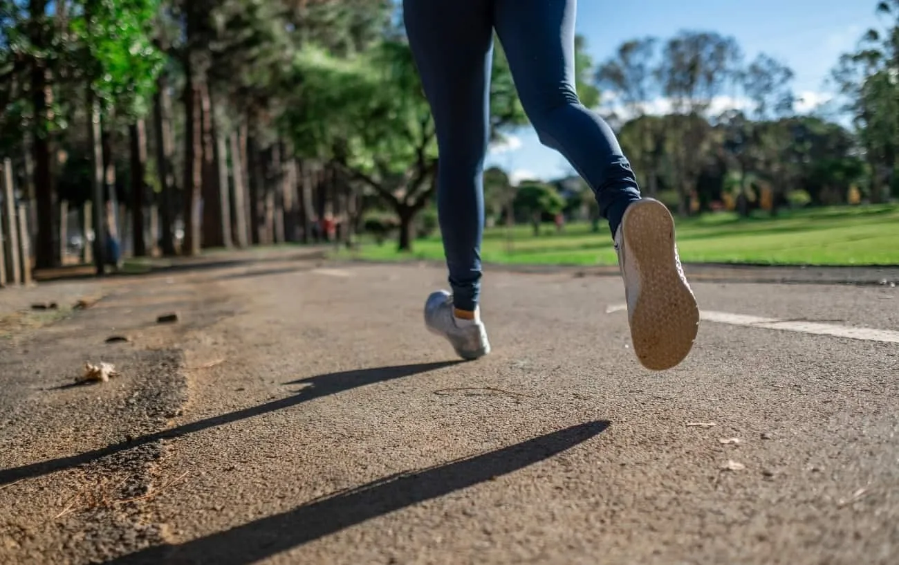 Крупный план человека's legs and feet running on the road.