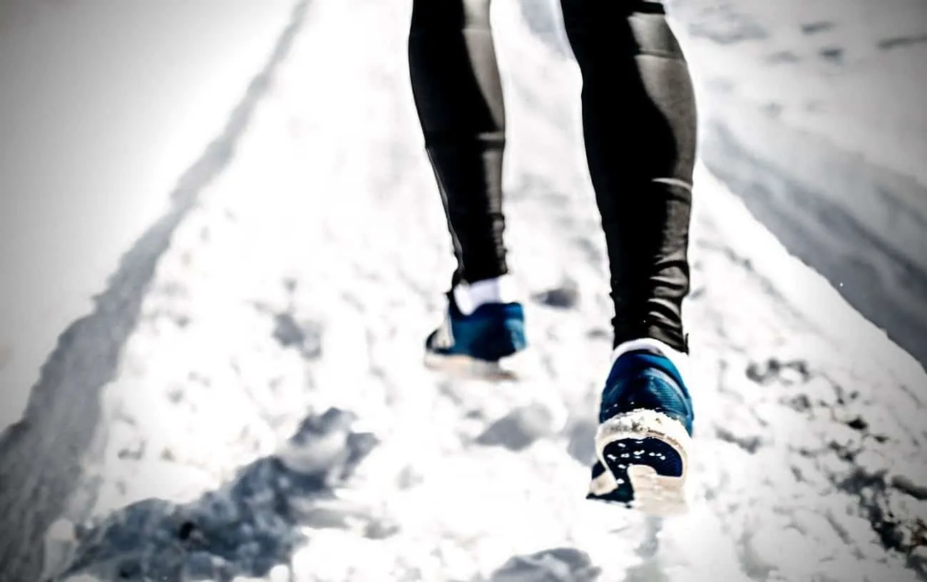 Крупный план человека's legs running through snow.