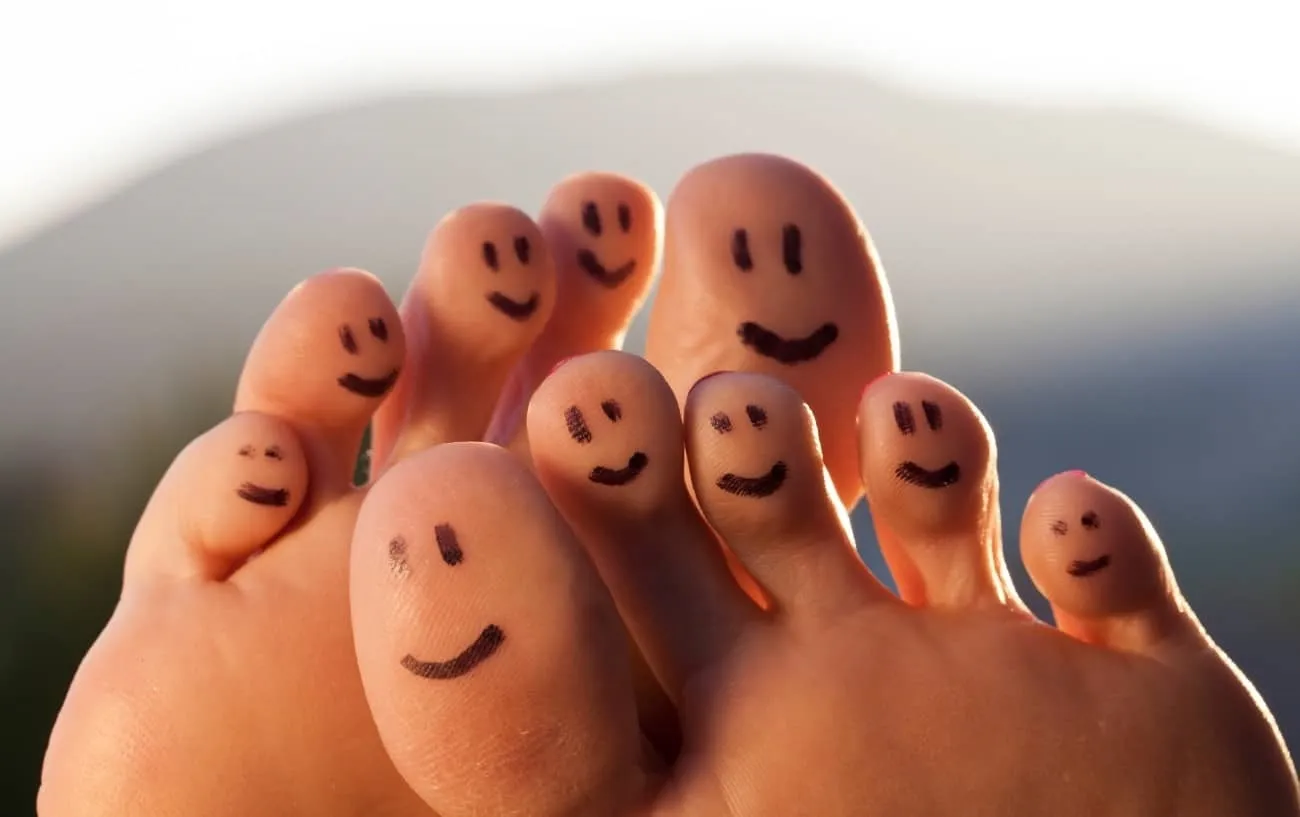 Человек's toes with smily faces drawn on them. 